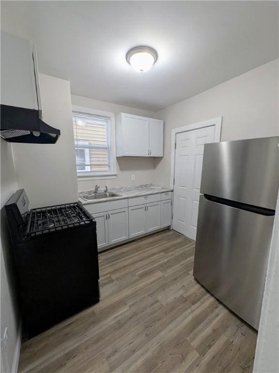 1216 Morrow St, Wilkinsburg, PA 15221 - kitchen featuring freestanding refrigerator, range with gas cooktop, a sink, light wood finished floors, and range hood