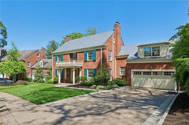 colonial house with a balcony, concrete driveway, a garage, brick siding, and a front lawn