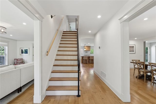 stairs featuring wood finished floors and recessed lighting