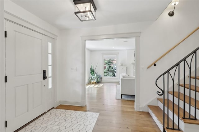 entryway featuring light wood-type flooring, baseboards, and stairway