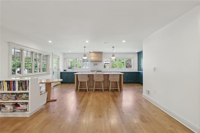 kitchen with light countertops, a center island, a kitchen breakfast bar, light wood-style floors, and recessed lighting
