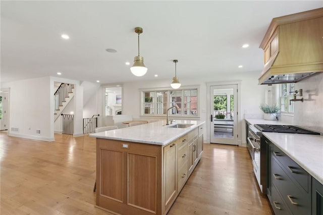kitchen with a sink, stainless steel range, light wood-style flooring, premium range hood, and recessed lighting