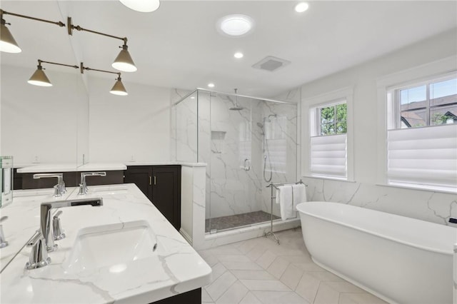 full bath featuring recessed lighting, a marble finish shower, a freestanding bath, and double vanity