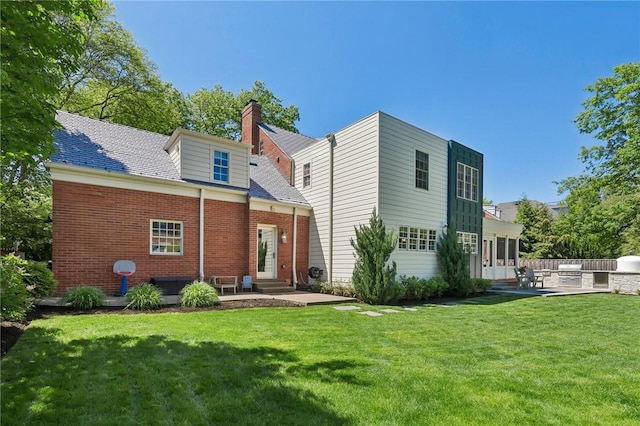 rear view of property featuring entry steps, a patio area, a yard, and a chimney