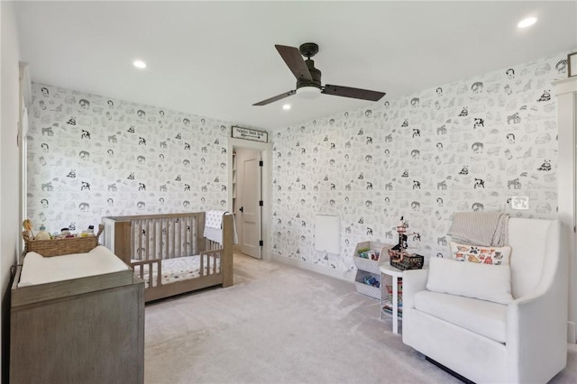 carpeted bedroom featuring wallpapered walls, recessed lighting, a crib, and a ceiling fan