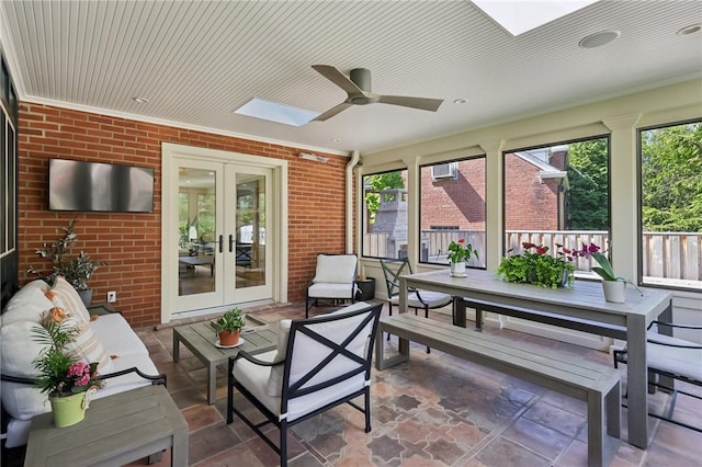 sunroom featuring a skylight, french doors, outdoor lounge area, and brick wall