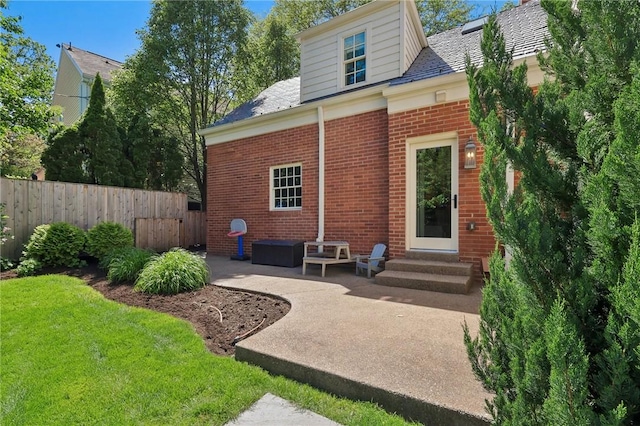 back of house with entry steps, brick siding, and a patio