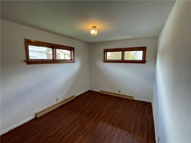unfurnished room with baseboard heating, dark wood-style floors, and baseboards