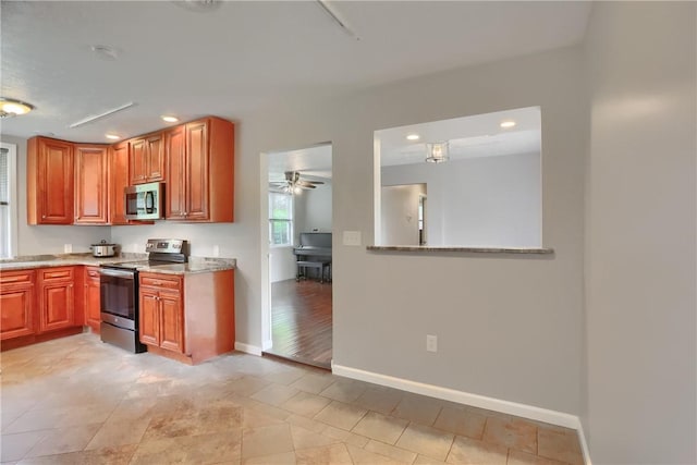 kitchen with appliances with stainless steel finishes, recessed lighting, baseboards, light stone counters, and ceiling fan