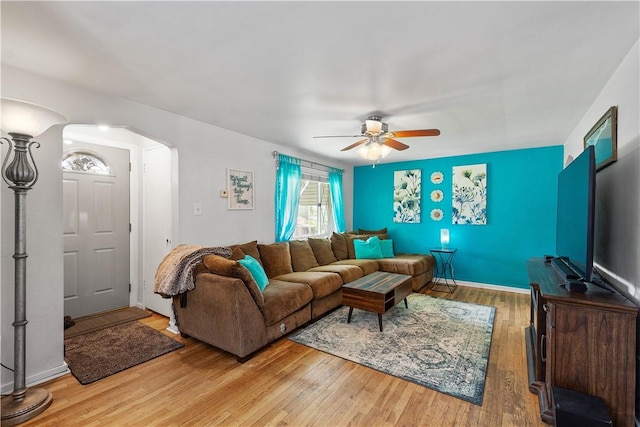 living room with a ceiling fan, wood finished floors, and arched walkways
