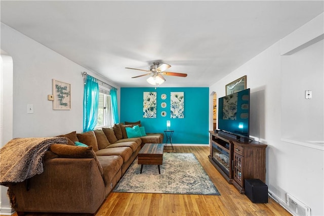 living area with a ceiling fan, arched walkways, and wood finished floors