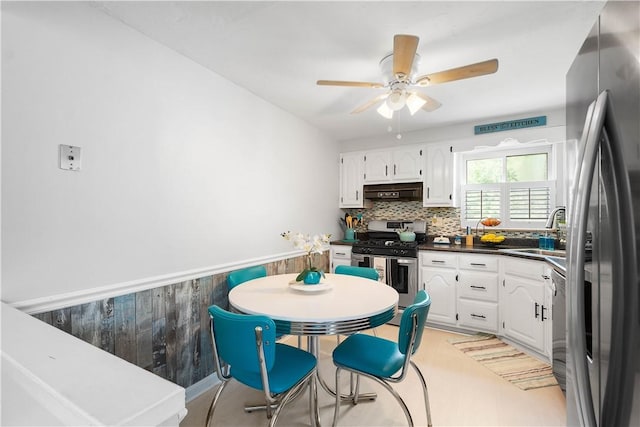 kitchen with appliances with stainless steel finishes, a sink, white cabinets, dark countertops, and a ceiling fan