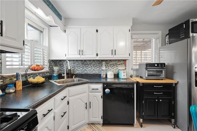 kitchen featuring black dishwasher, a sink, white cabinetry, decorative backsplash, and dark countertops
