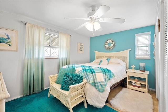 carpeted bedroom featuring multiple windows and ceiling fan