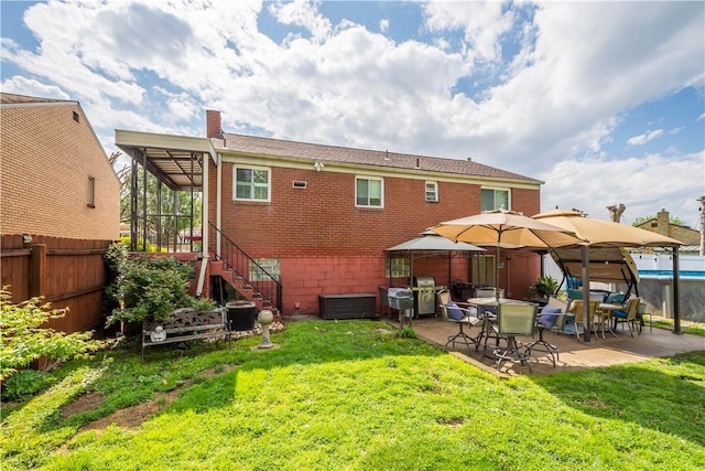 rear view of house featuring a patio area, stairs, brick siding, a gazebo, and a chimney