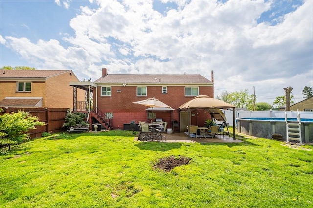 back of property with a gazebo, a chimney, brick siding, and stairway