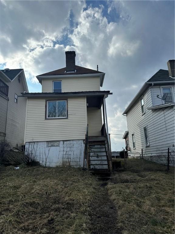 rear view of house featuring fence, a chimney, stairs, and a porch