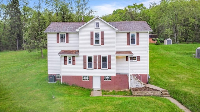 rear view of property featuring a lawn, a shed, and central AC