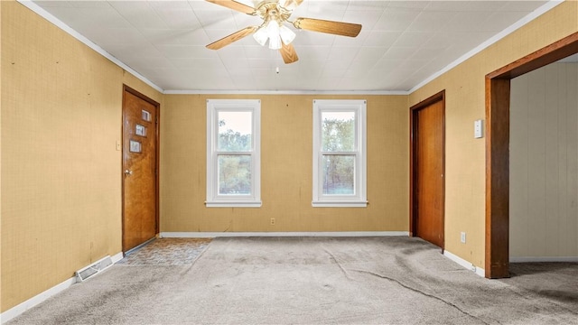 carpeted empty room with crown molding, a ceiling fan, and baseboards