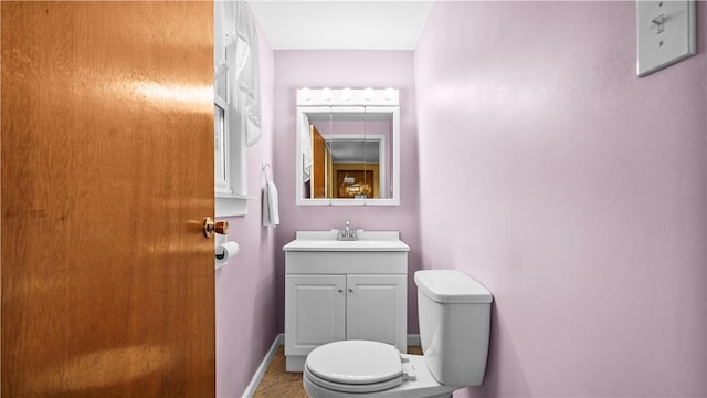 half bath featuring toilet, baseboards, and vanity