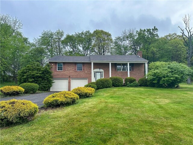 105 Audrey Ln, Jefferson Twp But, PA 16023 - split foyer home featuring a garage, a chimney, asphalt driveway, a front lawn, and brick siding