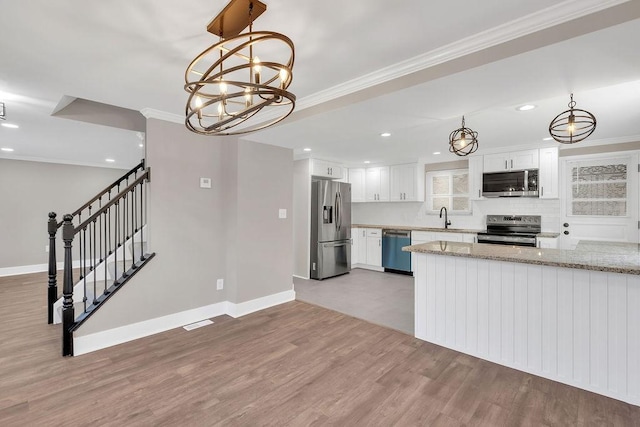kitchen with stainless steel appliances, a sink, light wood-type flooring, baseboards, and white cabinetry
