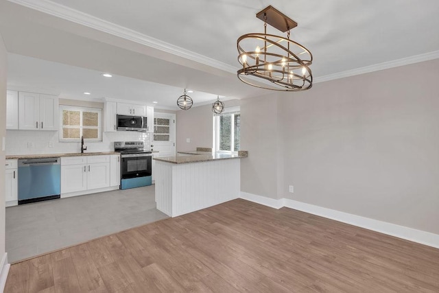 kitchen with appliances with stainless steel finishes, white cabinetry, a chandelier, backsplash, and ornamental molding