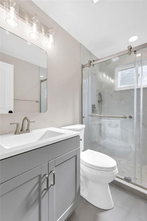 bathroom featuring toilet, a shower stall, vanity, and tile patterned flooring
