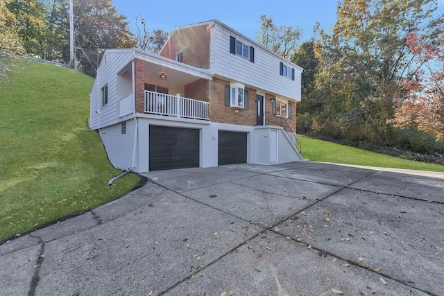 back of property featuring brick siding, a yard, a garage, and driveway