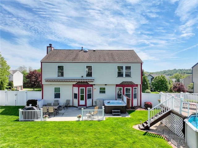 rear view of house featuring a hot tub, a chimney, a patio area, a gate, and a deck
