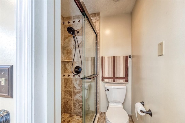 bathroom featuring a shower stall, toilet, and a textured ceiling