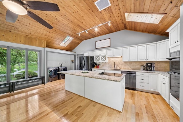 kitchen featuring a skylight, appliances with stainless steel finishes, separate washer and dryer, a sink, and wood ceiling