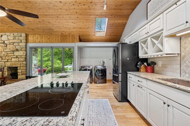 kitchen featuring black electric cooktop, washing machine and dryer, white cabinets, wood ceiling, and decorative backsplash