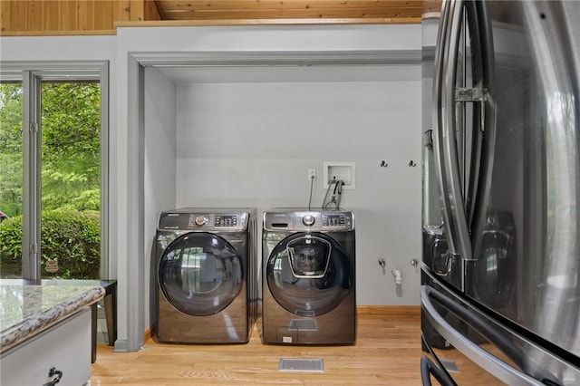 laundry room featuring washing machine and clothes dryer and light wood-style floors