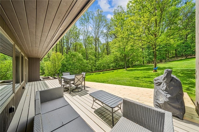 view of patio / terrace featuring outdoor dining area, a deck, and view of wooded area