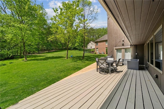 wooden terrace featuring outdoor dining space and a yard