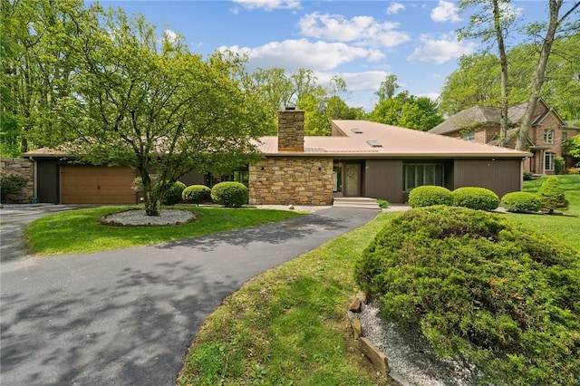 view of front facade with a chimney, stone siding, asphalt driveway, metal roof, and an attached garage
