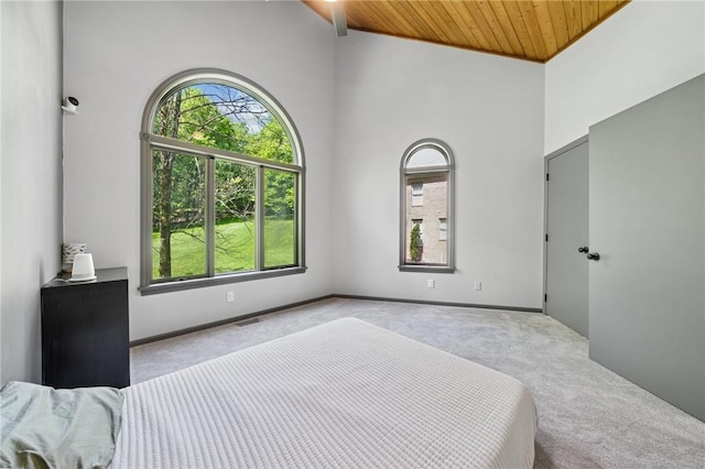 bedroom with carpet, wooden ceiling, a high ceiling, and baseboards