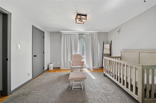 bedroom featuring a nursery area and wood finished floors