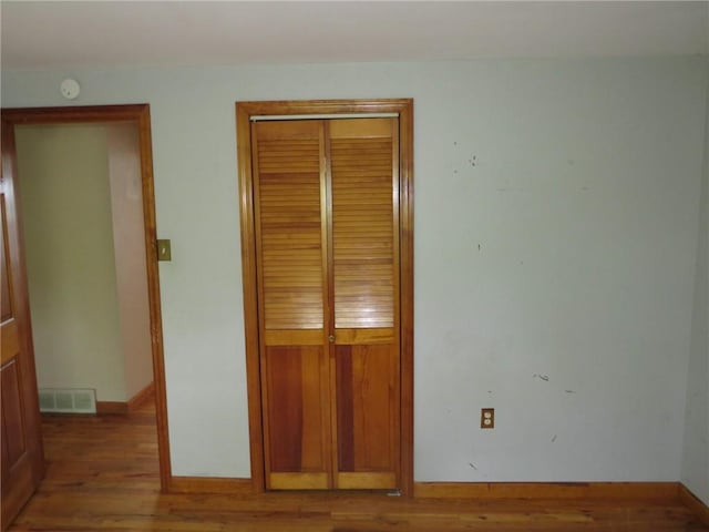unfurnished bedroom with wood finished floors, a closet, and baseboards