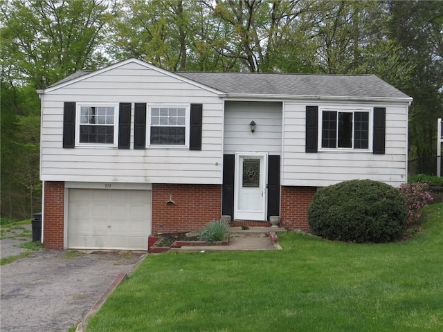 bi-level home featuring brick siding, a front lawn, an attached garage, and asphalt driveway