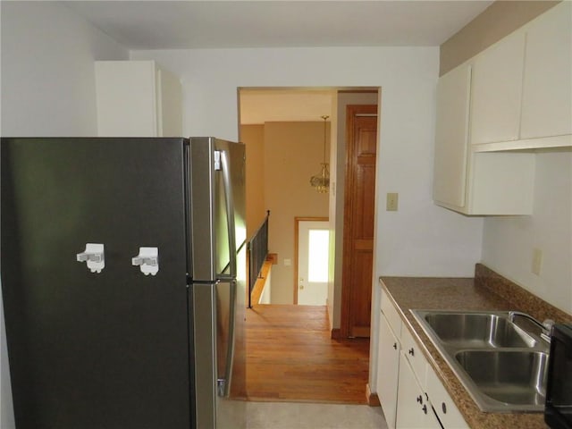 kitchen featuring freestanding refrigerator, a sink, white cabinetry, and dark countertops