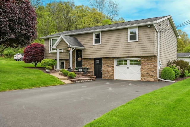 split foyer home with stone siding, a garage, a front lawn, and driveway