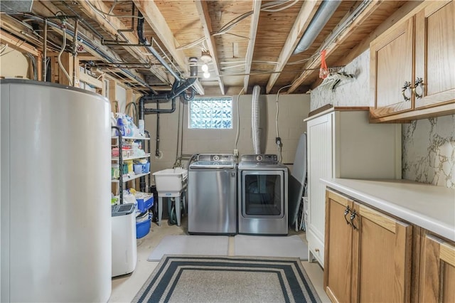 clothes washing area featuring washer and dryer, cabinet space, and gas water heater