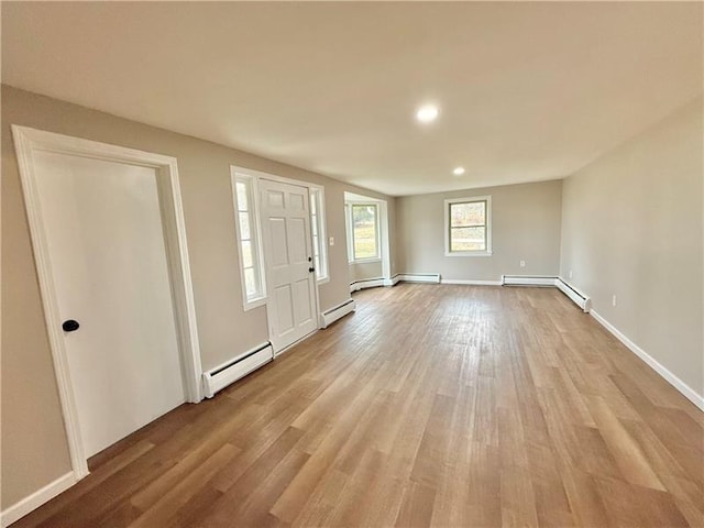 foyer with a baseboard heating unit, baseboard heating, light wood finished floors, baseboards, and recessed lighting