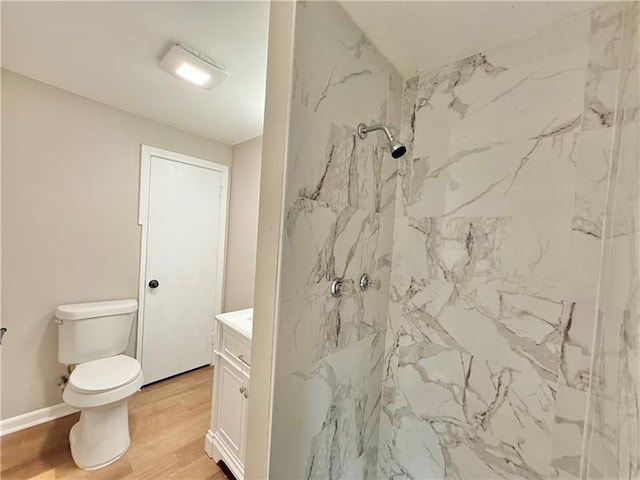 full bath featuring toilet, a marble finish shower, vanity, wood finished floors, and baseboards