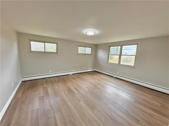 empty room featuring wood finished floors, baseboard heating, and baseboards