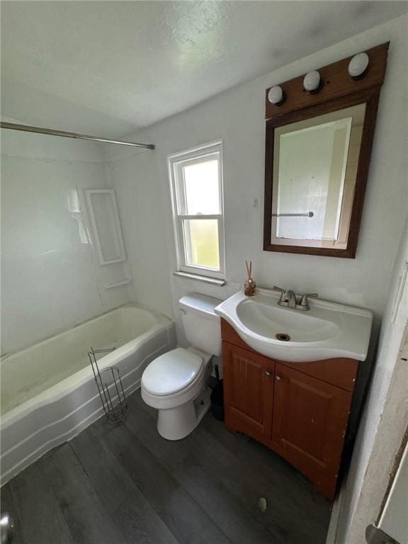 bathroom featuring wood finished floors, toilet, vanity, and shower / tub combination