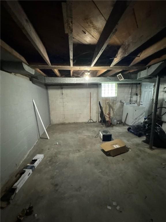 basement featuring washer / clothes dryer and concrete block wall