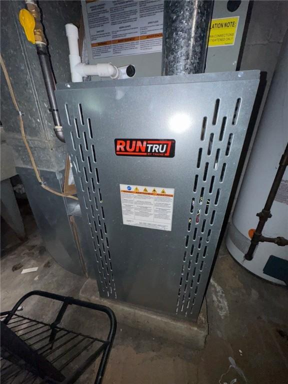 utility room featuring heating unit and water heater